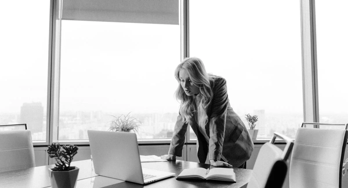 Businesswoman strategizing in a bright office with city views.