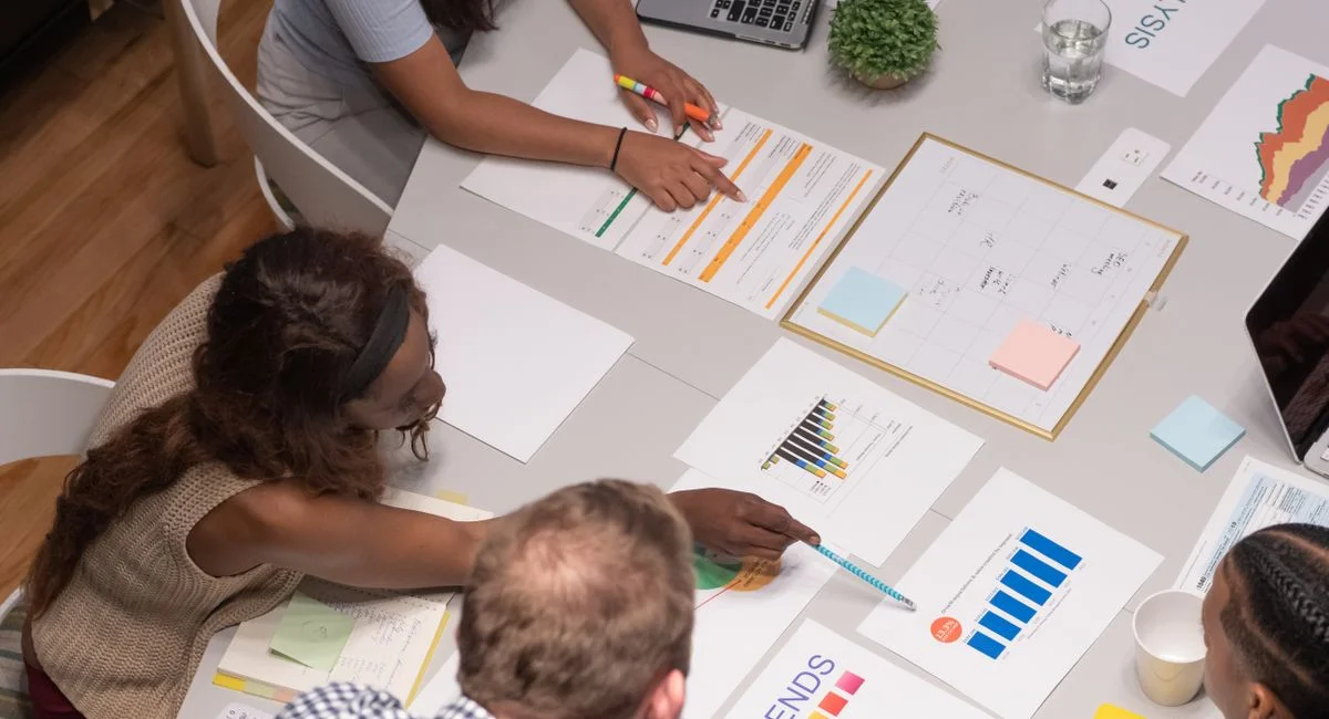 Team of professionals collaborating on a business project, analyzing charts and graphs in an office setting.