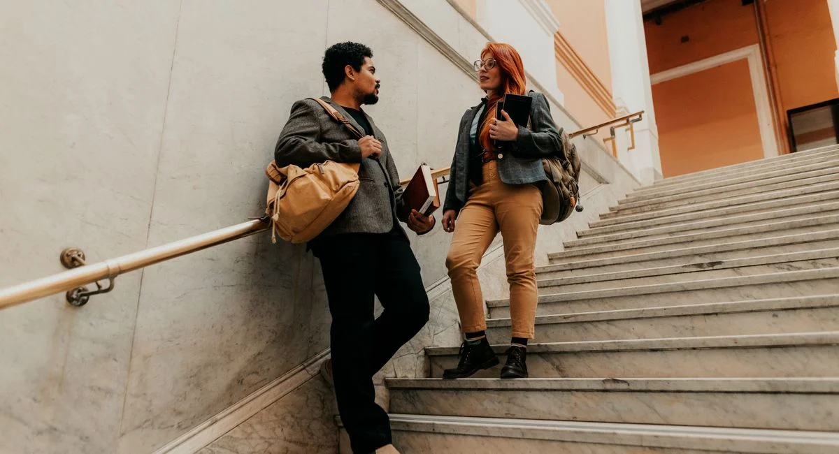 Two university students walking and conversing on an indoor staircase. Captured in Buenos Aires.